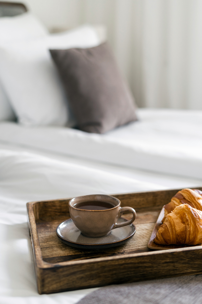 Bandeja con café y croissants sobre la cama